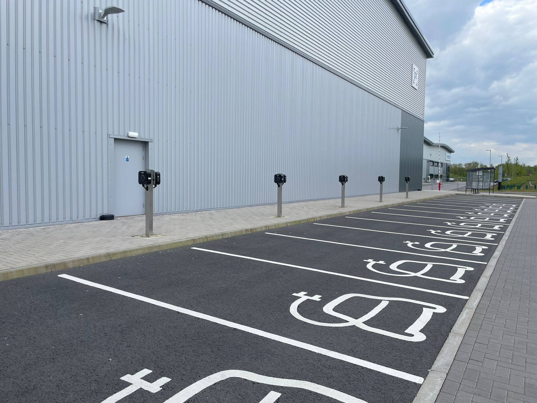A cluster of fourteen 7kW AC charging units strategically positioned at a large distribution center, serving both public and private use. These charging stations cater to a diverse range of electric vehicles, facilitating convenient charging for employees, visitors and the general public. Located at a pivotal hub, they support the adoption of sustainable transportation practices within the community while reinforcing the distribution center's commitment to environmental stewardship and innovation.